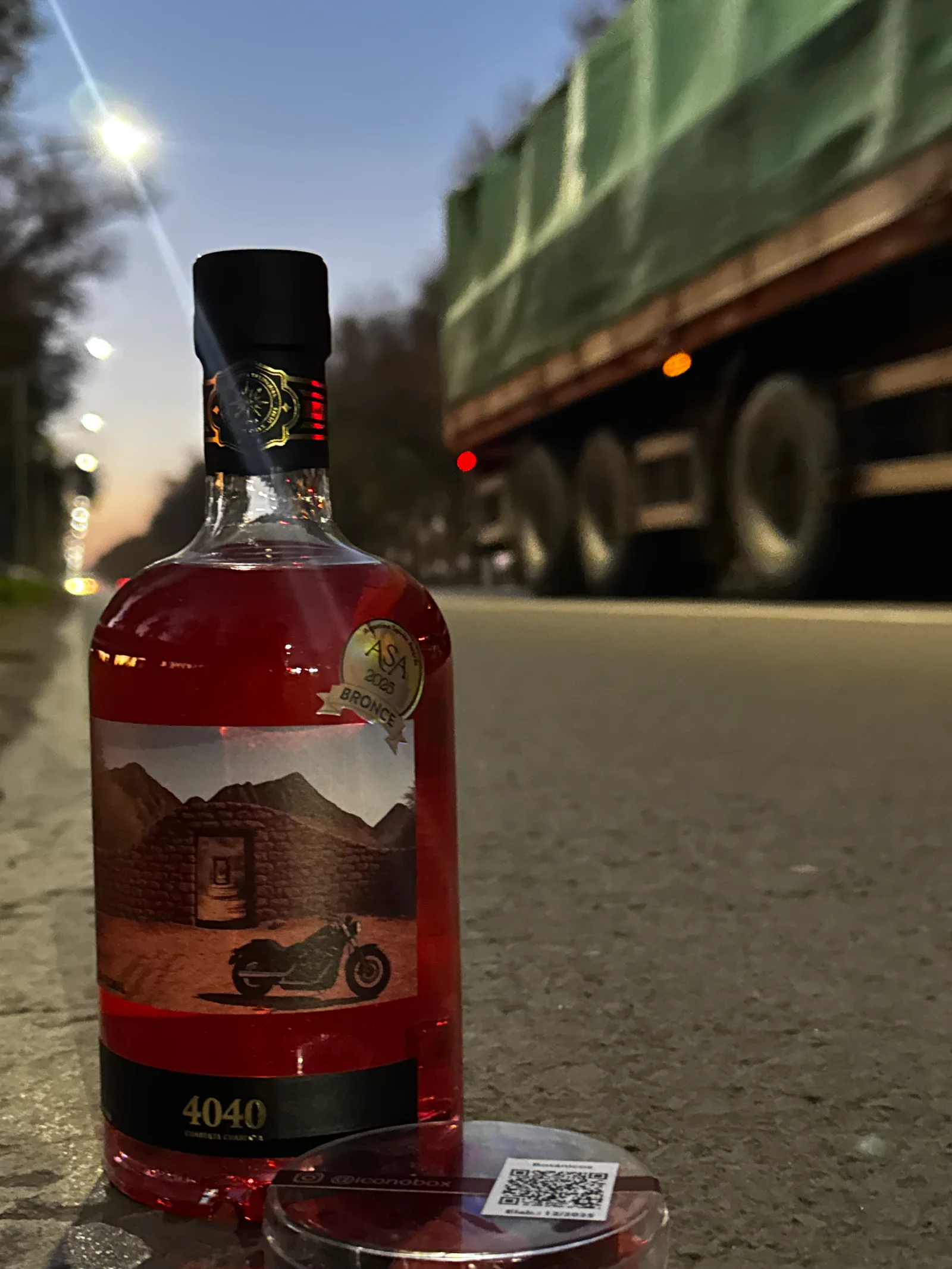 Botella rosada de Gin 4040 Floral con brillo perlado en una escena urbana nocturna
